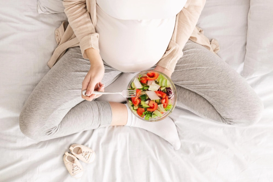 беременная девушка держит тарелку с овощами