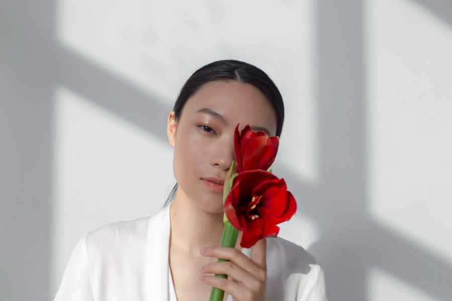 женщина в белом держит красный цветок