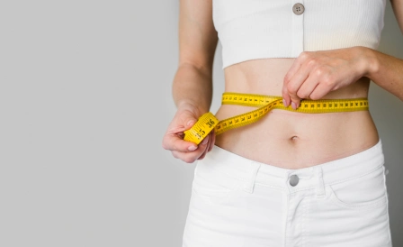 стройная девушка измеряет талию