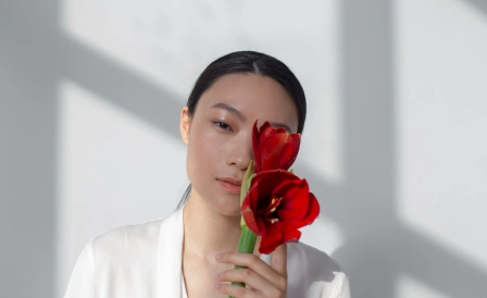 женщина в белом держит красный цветок