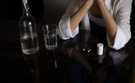 мужчина сидит за столом с бутылкой и стаканом алкоголя