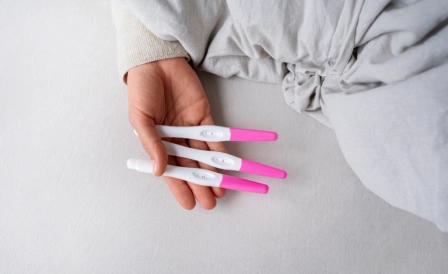 девушка держить положительные тесты на беременность