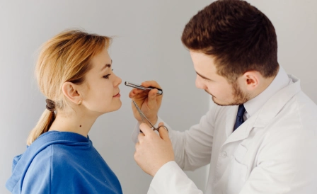 мужчина доктор проводит ларингоскопию девушке