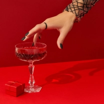 женщина тянет руку к бокалу с алкоголем