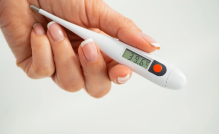 женщина держит градусник после измерения базальной температуры